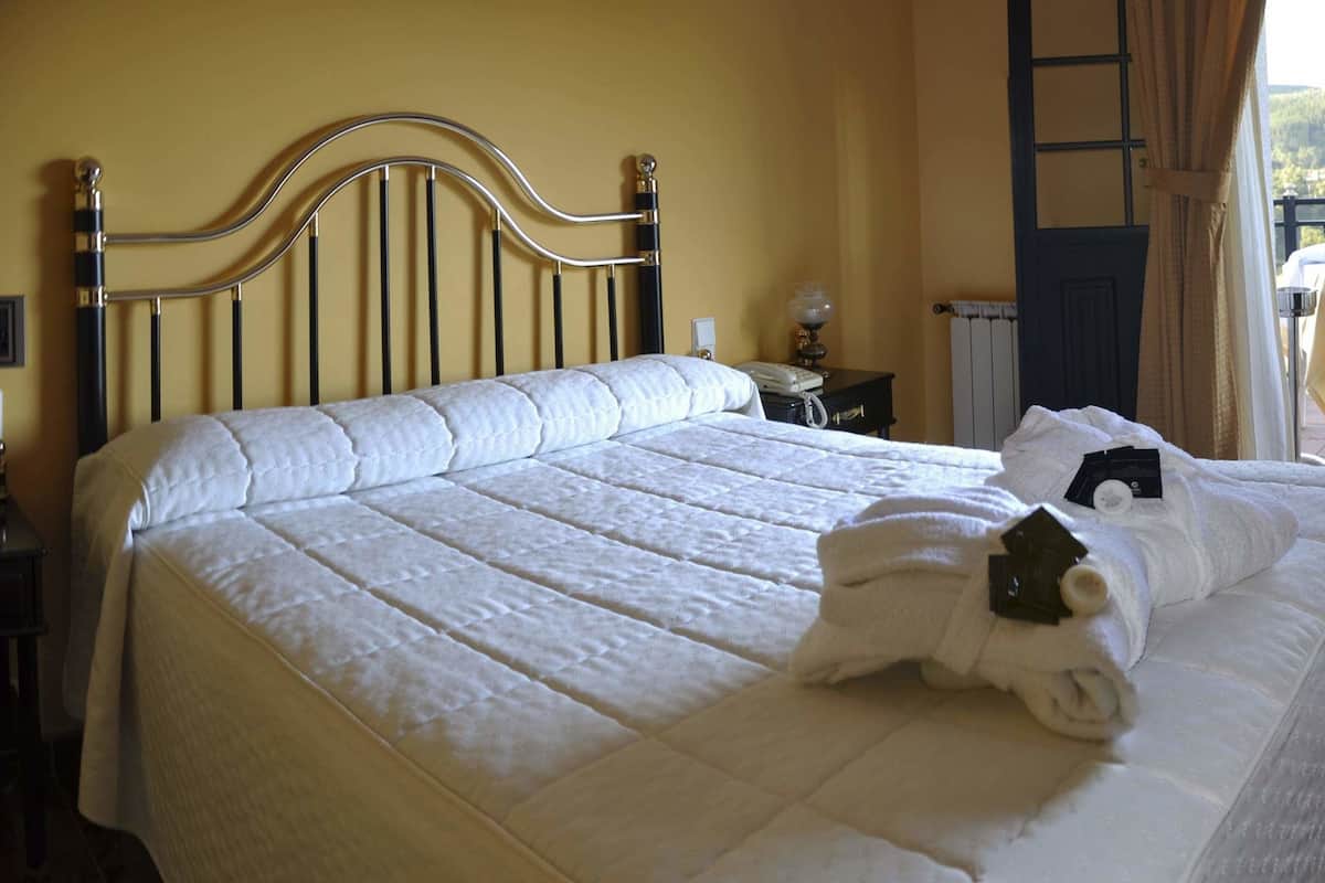 Ein Hotelzimmer mit einem Bett, einem Sessel, einem Fernseher und einem Balkon mit Tisch und Stühlen.