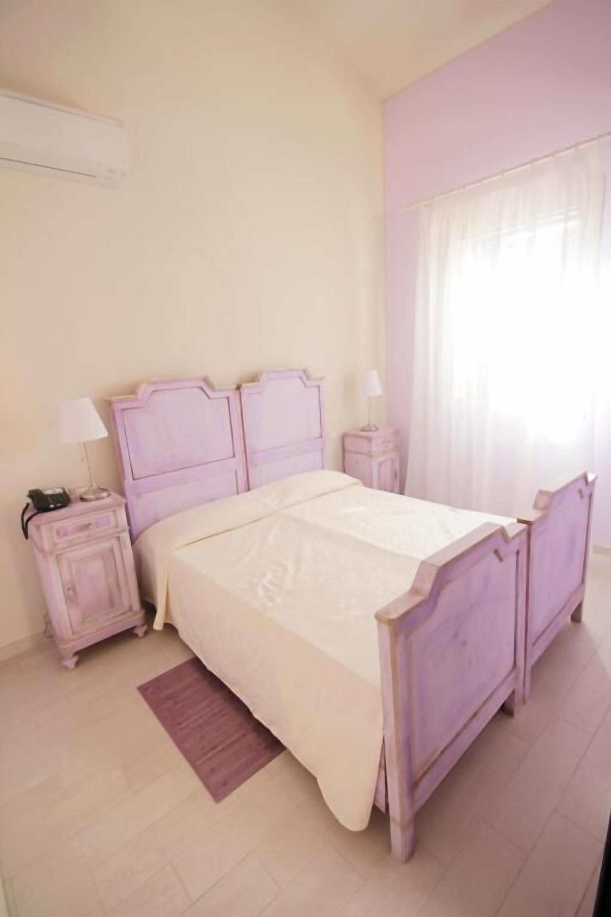 Une chambre à coucher avec un lit, des tables de chevet et une fenêtre avec des rideaux.