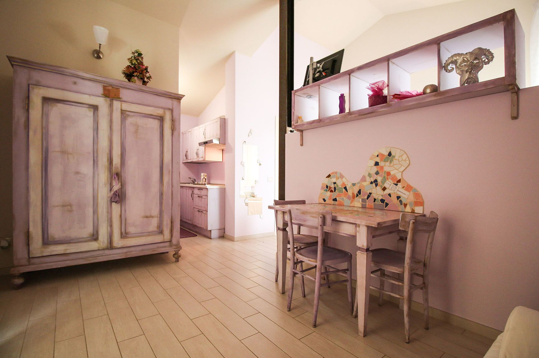 Un'area pranzo con tavolo e sedie in legno, un armadietto con specchio e uno scaffale con oggetti decorativi.