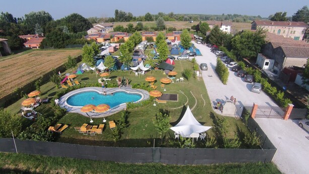A campsite with a swimming pool, tents, and outdoor seating areas.