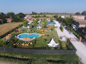 A campsite with a swimming pool, tents, and outdoor seating areas. - Lucciole nella nebbia (Bondeno)