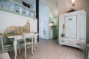 Una habitación con una mesa de comedor, sillas, un armario y una estantería en la pared.
