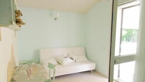 A room with a bed, a table with chairs, and a door leading outside.