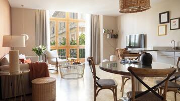 A modern living room with a dining area, large windows, and a television.