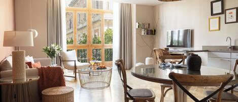 A modern living room with a dining area, large windows, and a television.