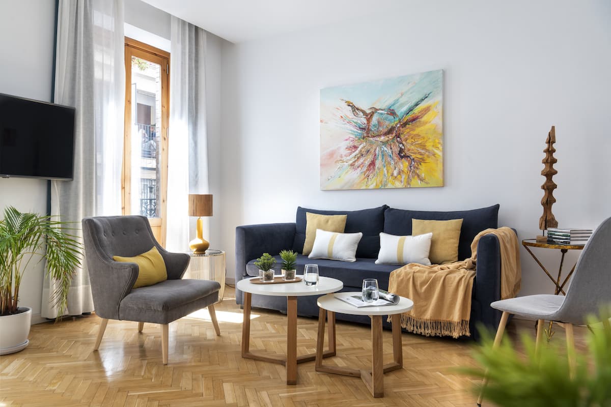 A modern living room with a sofa, armchairs, a coffee table, and a painting on the wall.