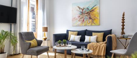 A modern living room with a sofa, armchairs, a coffee table, and a painting on the wall.