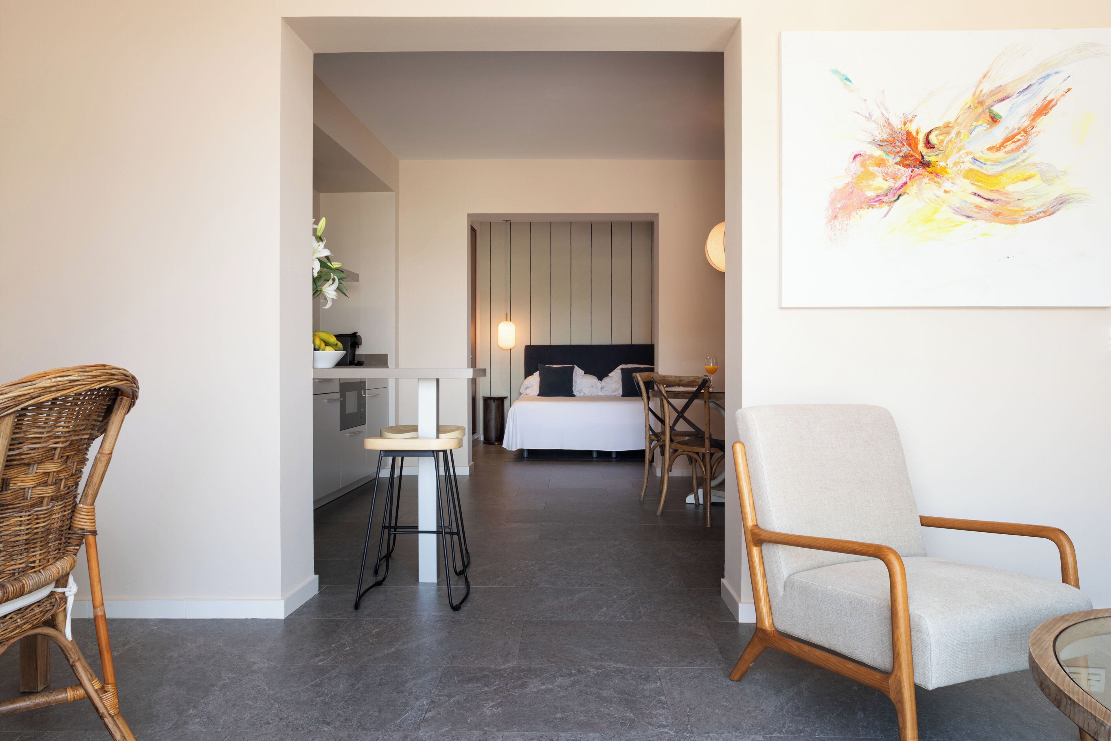 A modern hotel room with a bed, a dining area, and a living space.