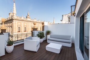 Relax on the rooftop terrace with a sofa, armchairs, and a small table overlooking historic architecture.
