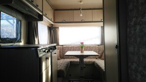 Interni compatti di un camper con angolo cottura, zona pranzo e area salotto.