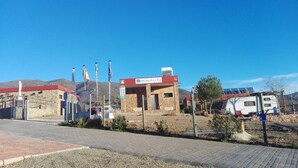 Un campeggio con un edificio in pietra con la scritta "Almocita" e un'area recintata con bandiere.