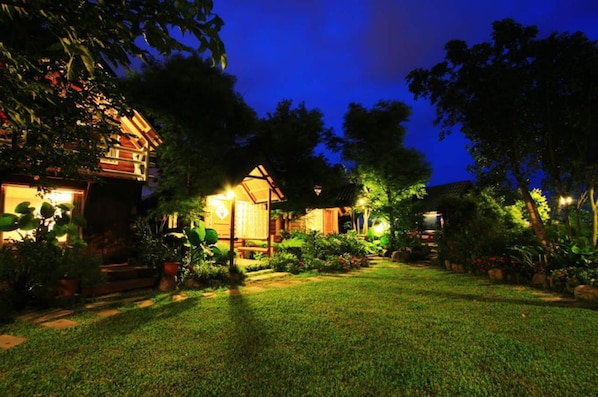 Stroll through a serene garden area surrounded by lush greenery and a wooden fence.