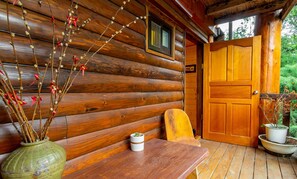 Une cabane en bois avec un banc en bois, une table et une porte.
