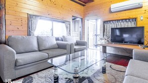 A modern living room with a grey sofa, a glass coffee table, and a flat-screen TV. - Water Villa (Wujie)