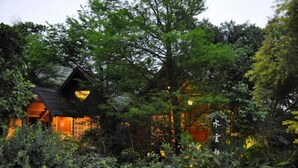 A traditional Japanese-style house surrounded by lush greenery and flowering plants. - Water Villa (Wujie)
