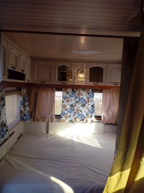 A bedroom with a bed, floral curtains, and a window with a view.