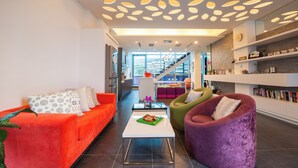 Ein modernes Wohnzimmer mit heller Decke, einer Treppe und einem Bücherregal.