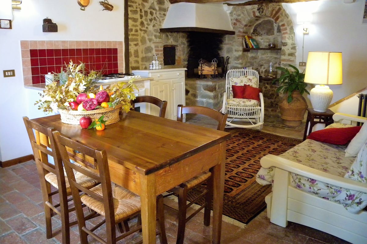 Una sala de estar acogedora con una mesa de comedor de madera, un sofá blanco y una chimenea de piedra.