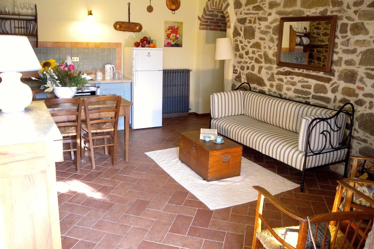 Una sala de estar acogedora con un sofá, una mesa de centro de madera y un comedor con sillas y una mesa.