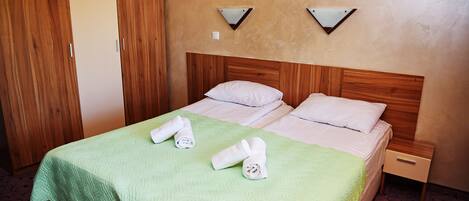 Une chambre d’hôtel avec un lit, deux tables de chevet, une armoire en bois et une couvre-lit verte.