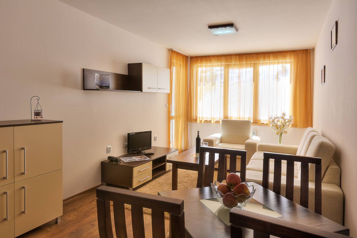A modern living room with a dining area, a flat-screen TV, and a sofa.