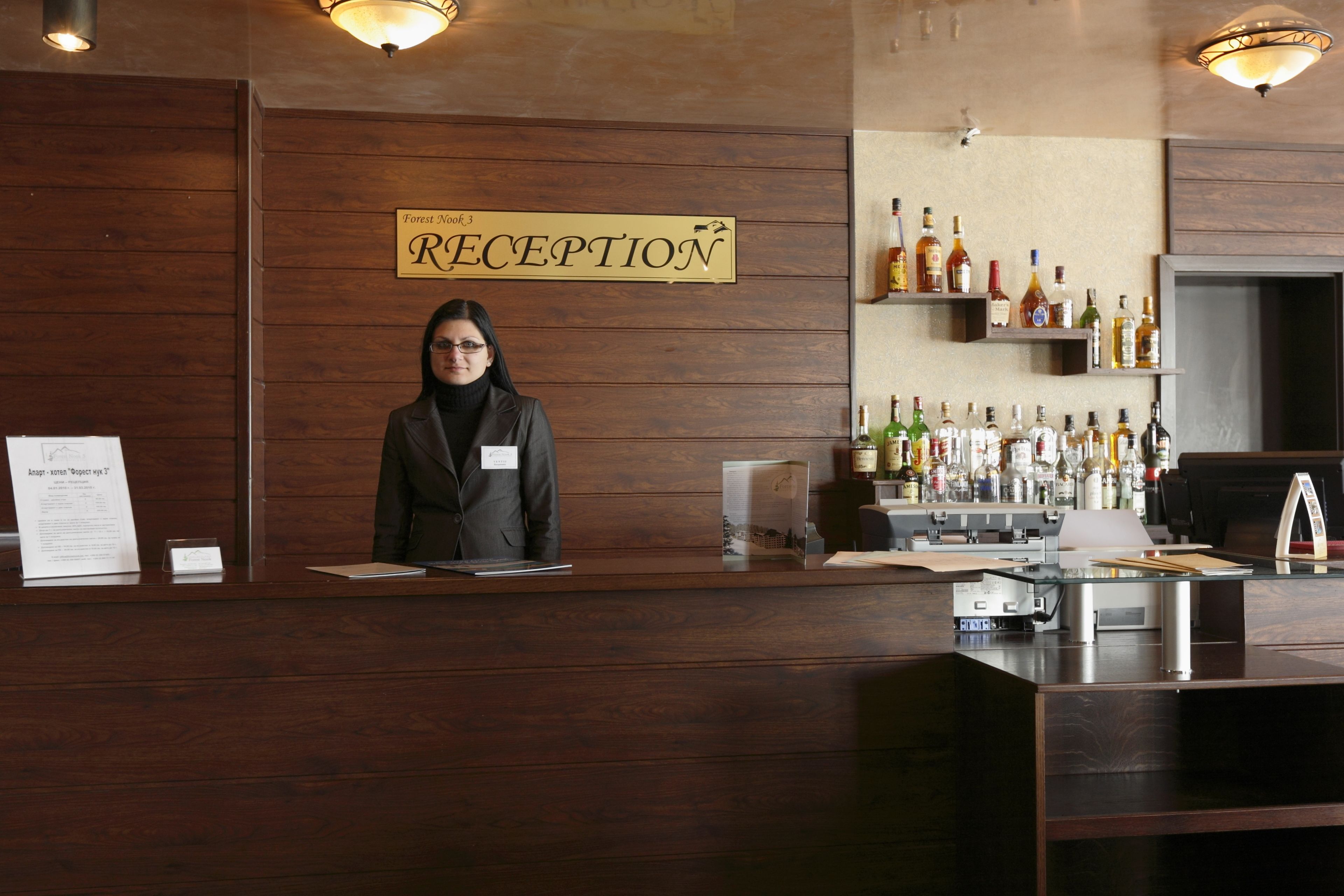 A reception desk with a sign reading "RECEPTION" and a woman standing behind it.