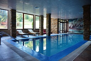 An indoor swimming pool with stone pillars, lounge chairs, and a mural on the wall. - Forest Nook (Smolyan)
