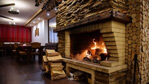 Una habitación acogedora con chimenea de piedra, muebles de madera y un comedor con cortinas rojas.