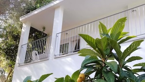 A white building with a balcony and a tree with green leaves and yellow fruits. - In Campagna da Nino (Olbia)