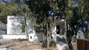 A modern building with a white facade, stone steps, and a gravel area. - In Campagna da Nino (Olbia)