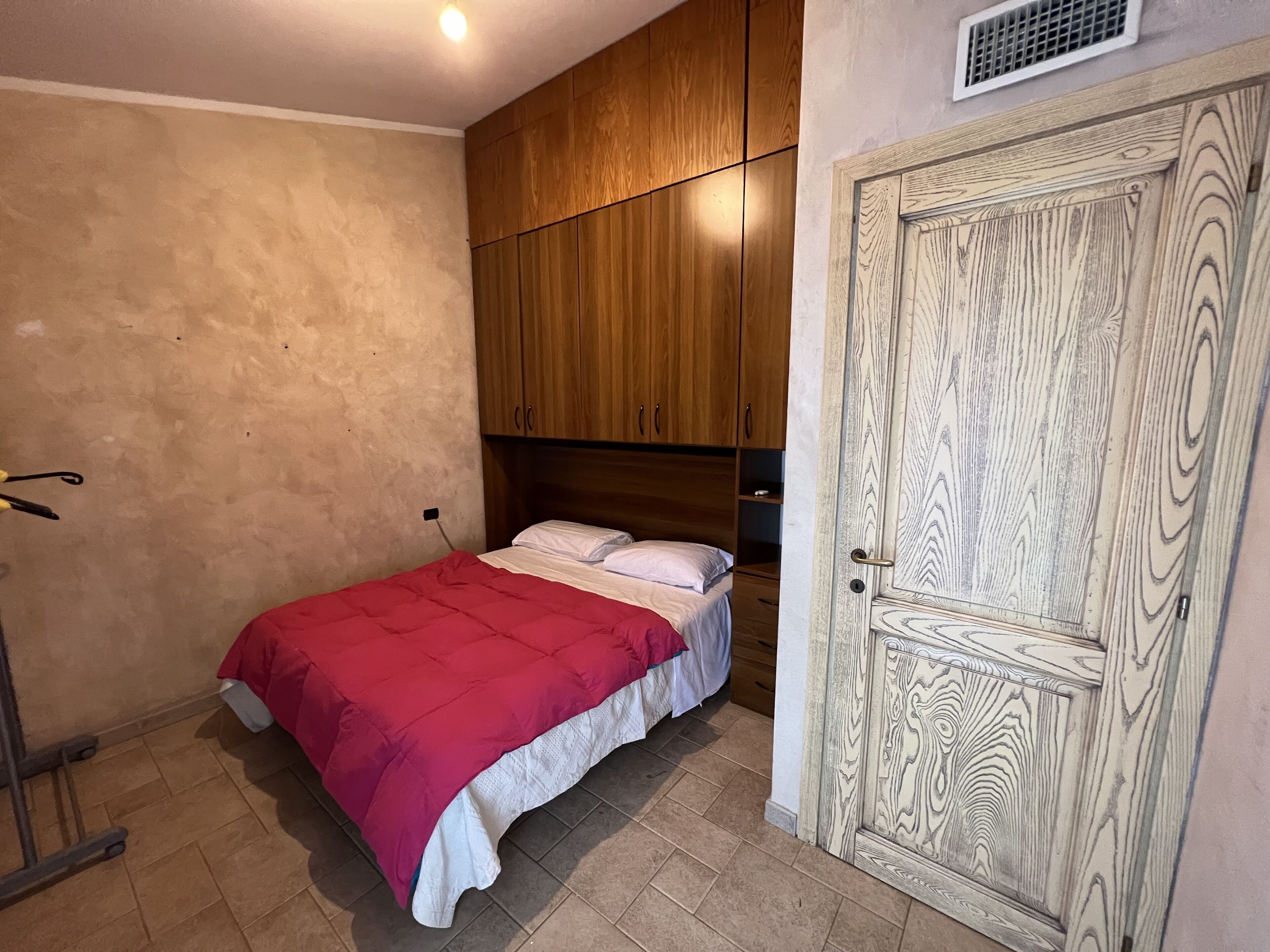 Un dormitorio con cama, armario de madera y una puerta de diseño detallado.