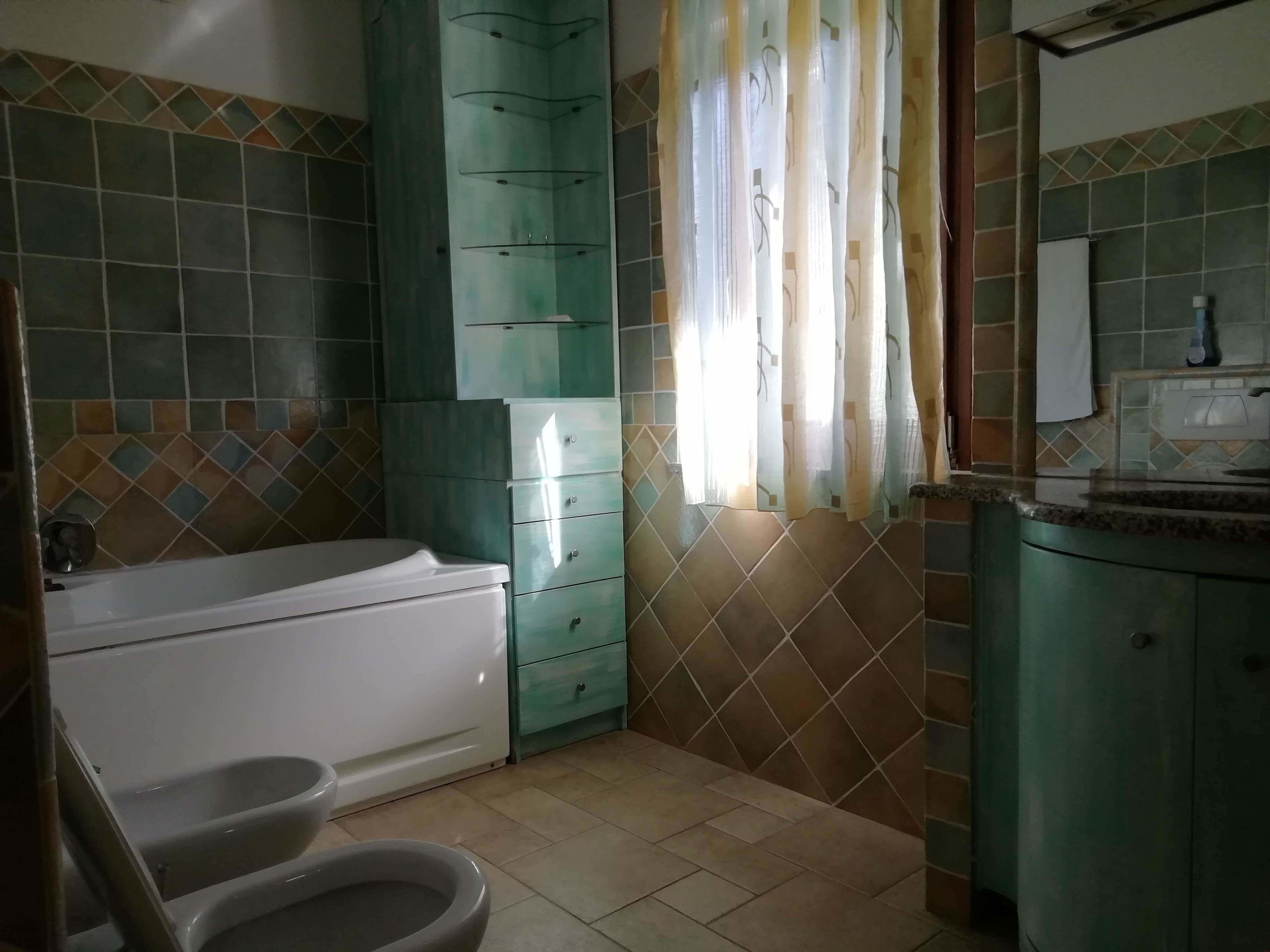 Et badeværelse med badekar, toilet og håndvask.