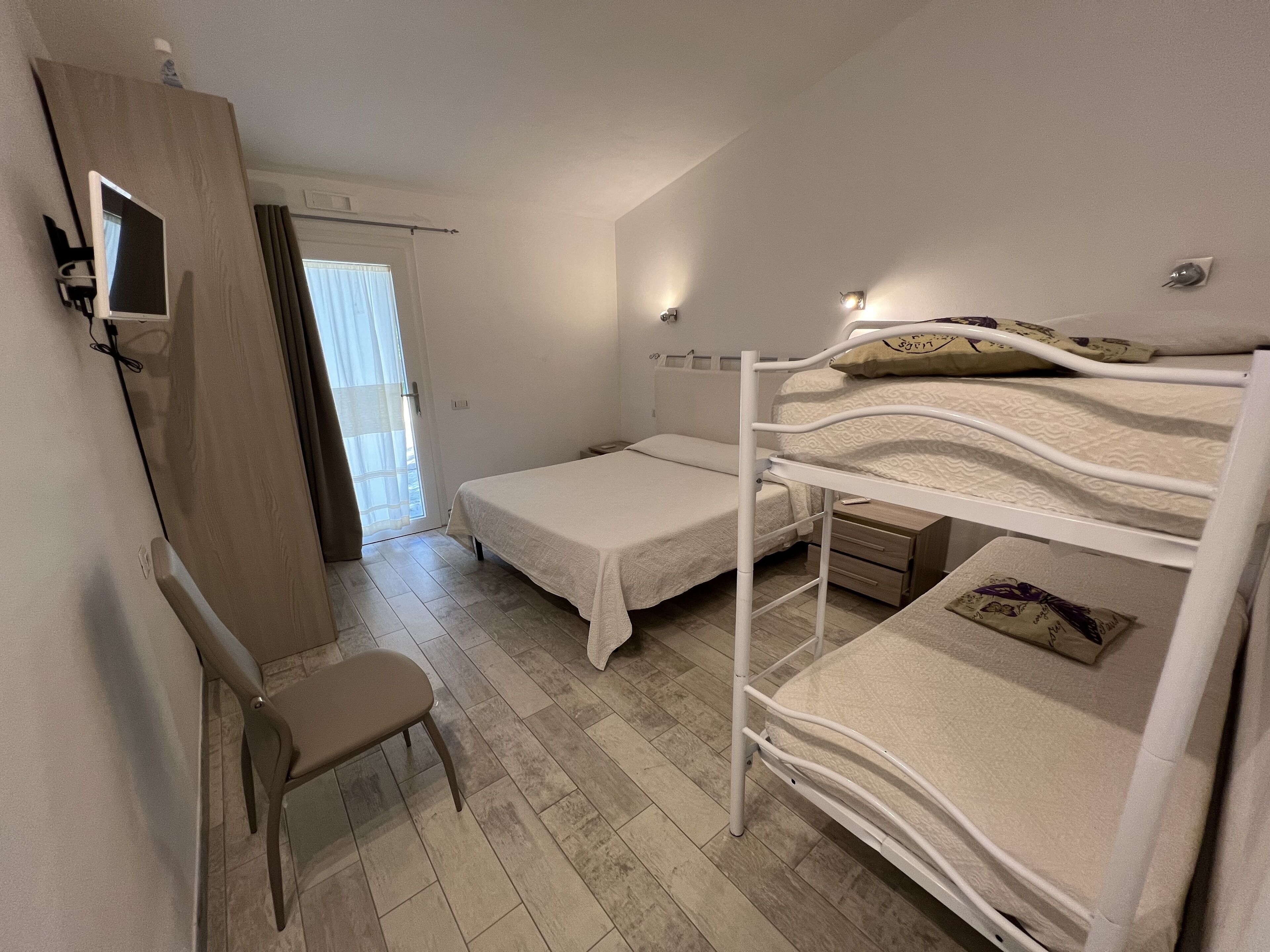 A bedroom with a bunk bed, a desk, and a chair.