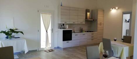 A modern kitchen with white cabinets, a built-in stove, and a dining area with a table set for two.