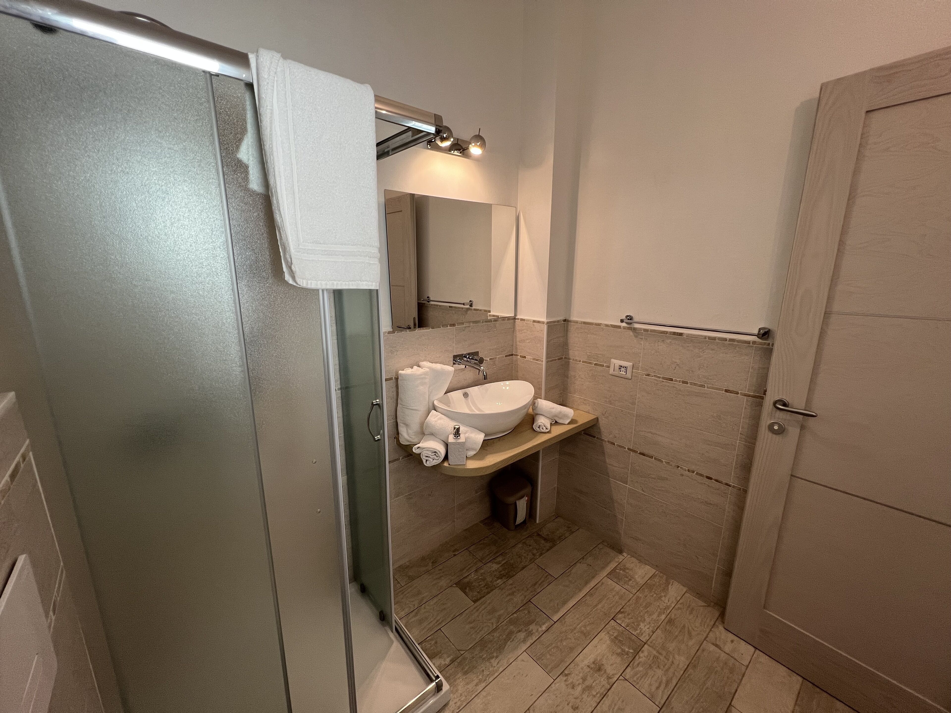 Un baño con ducha de vidrio, lavamanos y espejo.