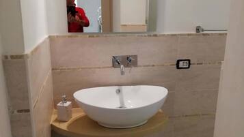 Ein Badezimmer mit einem weißen Waschbecken, einem Spiegel darüber und einem Handtuchhalter an der Wand.