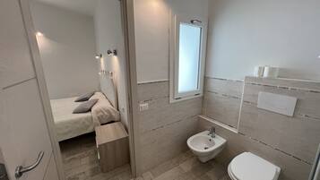 Une salle de bain moderne équipée d’un bidet, de toilettes et d’un espace douche.