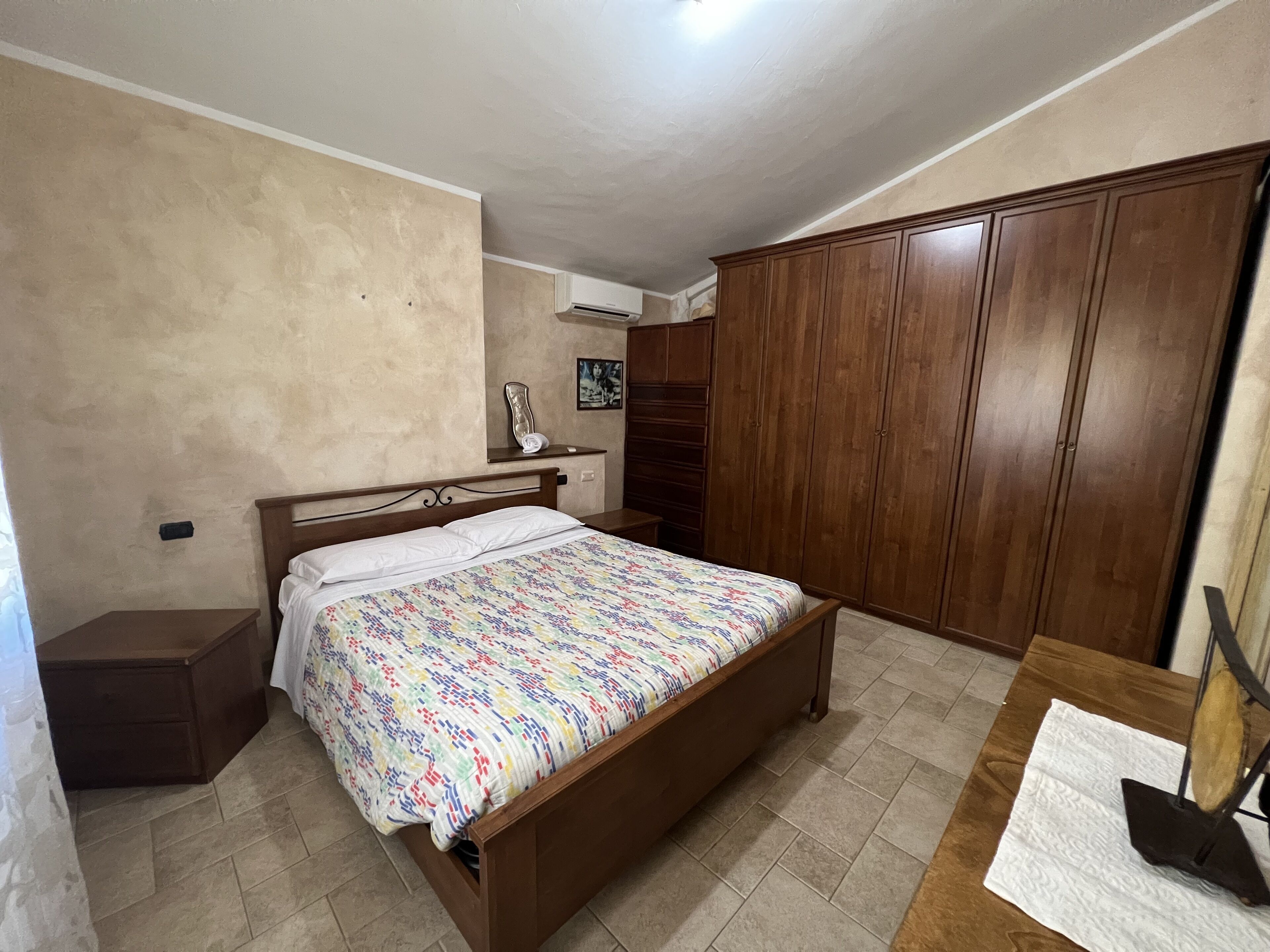 Un dormitorio con cama, armario de madera y una mesita de noche.