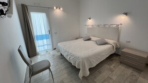 A bedroom with a bed, a chair, a bedside table, and a nightstand. - In Campagna da Nino (Olbia)