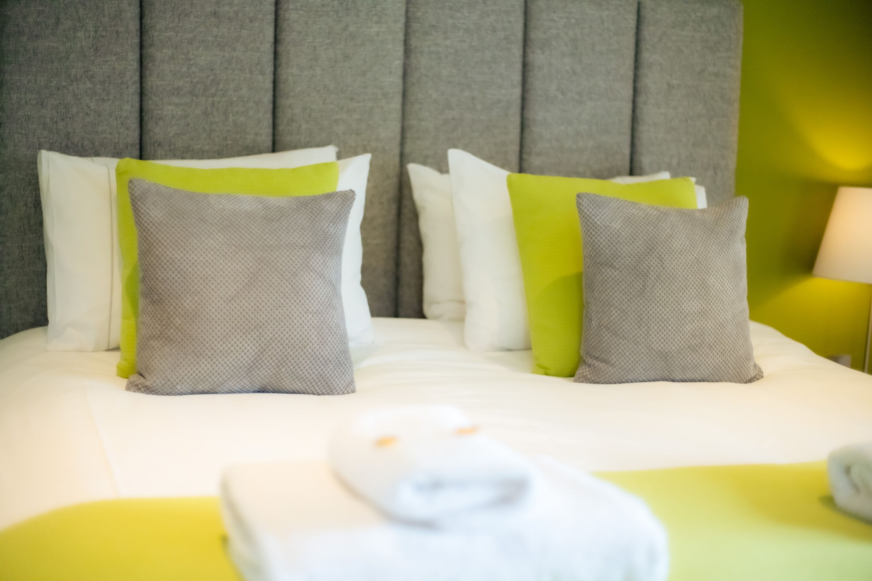 A neatly made bed with pillows and a folded towel.