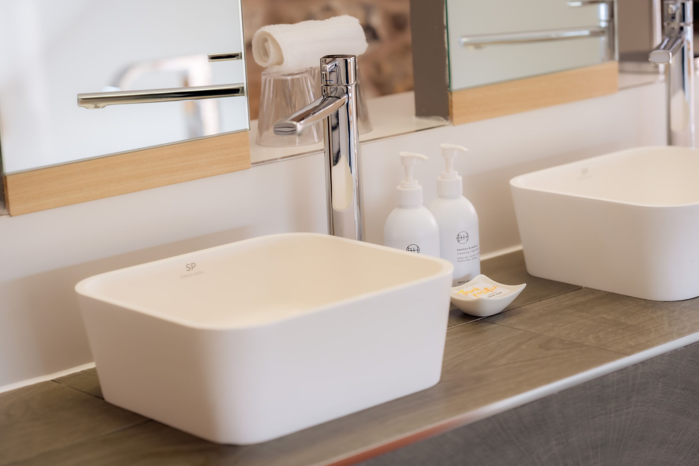 A modern bathroom with two white sinks, a chrome faucet, and a mirror above the sink.