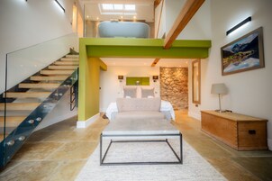 A modern interior with a staircase, a bed, a stone wall, and a painting.