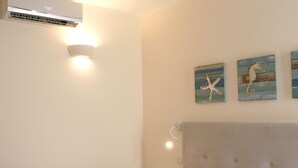 Un dormitorio con cama, aire acondicionado, ventilador de techo y obras de arte en la pared.