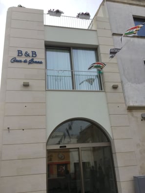 En bygning med et skilt, der viser "B&B Casa di Emma", og en balkon med et flag.