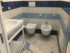 Et badeværelse med toilet, bidet og håndvask.
