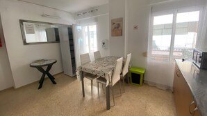 Un comedor con una mesa y sillas, una mesita auxiliar, un ventanal con vistas y una puerta que da a otra habitación.