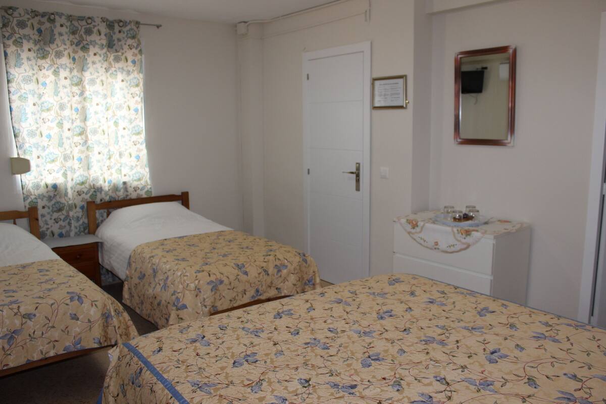 A room with two beds, a small table with a mirror, and a door.
