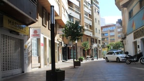 Una calle urbana con edificios, un automóvil estacionado y una motocicleta.