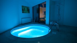 A modern bathroom with a freestanding bathtub, a shower, and a glass door leading to a garden. - Wolkendorf Bio Hotel & Spa (Vulcan)