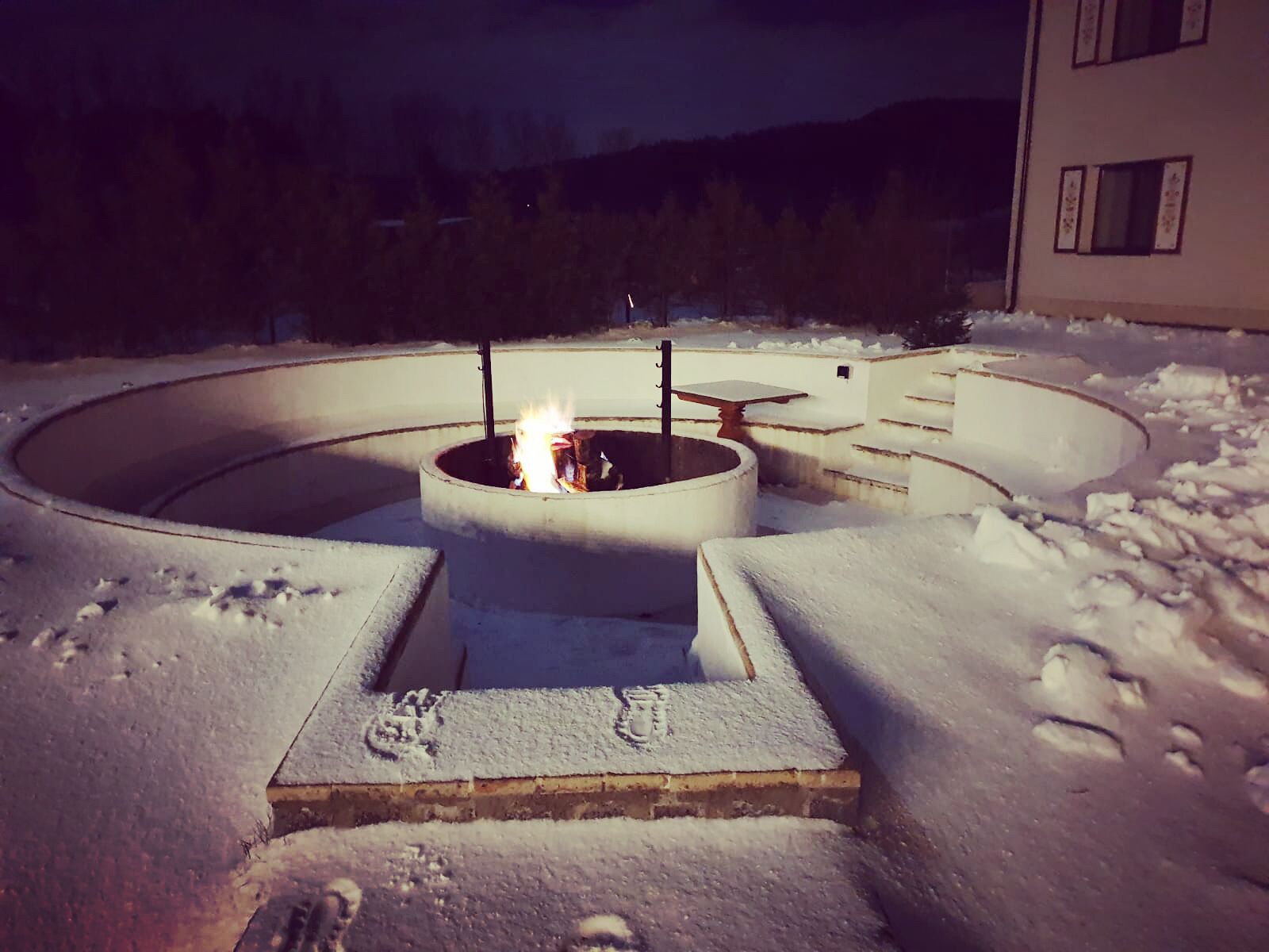 Fuego en un pozo circular al aire libre rodeado de nieve.